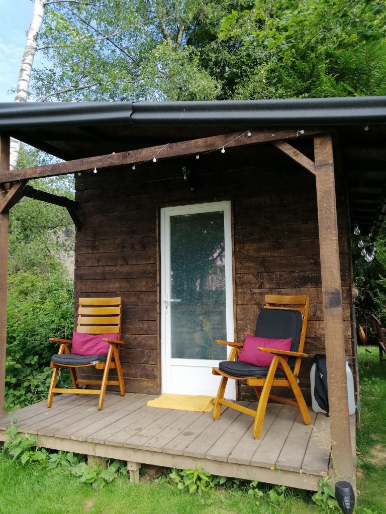 la terrasse de La Cabane Félicie avec deux sièges encadrant la porte d'entrée